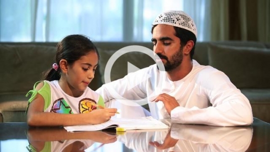 Arab father helping his daughter with her homework|