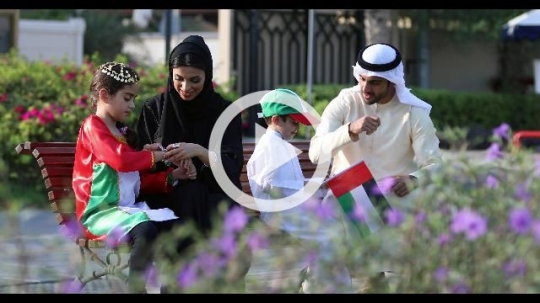 Arab family sitting on the bench celebrating the UAE National Day|