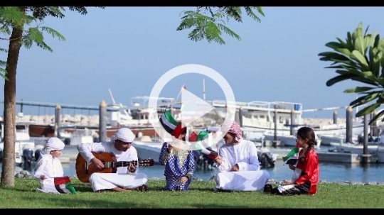 Middle Eastern family and friends sitting on the grass celebrating the UAE National Day|