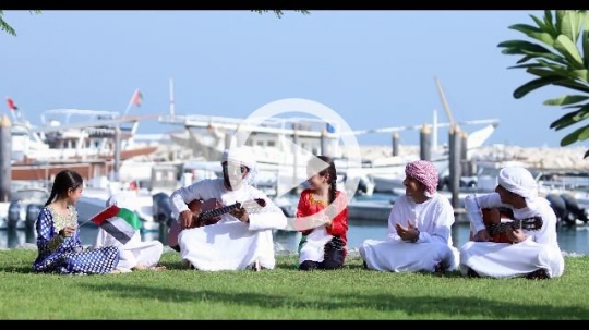 Arab family sitting on the grass celebrating the UAE National Day|