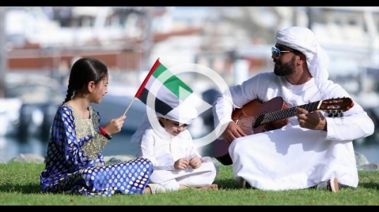 Arab family sitting on the grass celebrating the UAE National Day|