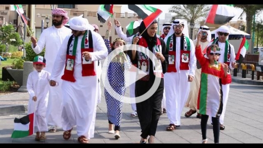 Family celebrating the UAE National Day during a parade|