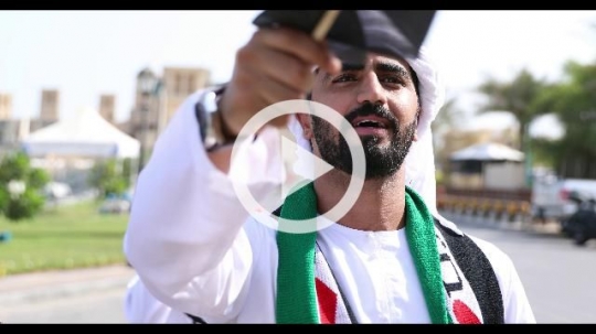 Three arabs celebrating the UAE National Day during a Parade|