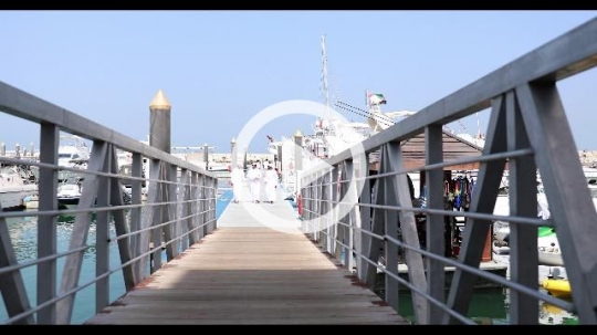 Arab friends dressed in the traditional attire walking on the dock|
