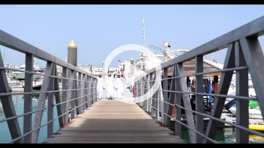 Arab men dressed in the traditional UAE attire walking on the dock|