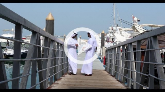 Arab men standing by the dock talking to each other|