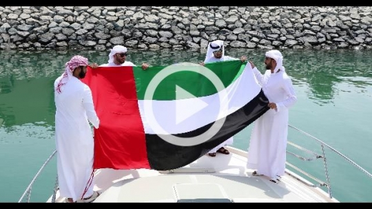 Arab men carrying the UAE Flag on the yacht|