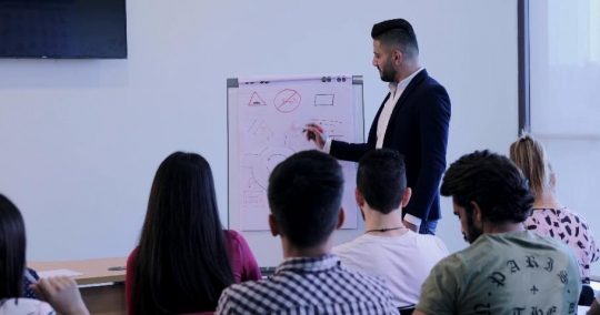 Students focusing in the classroom and girl raising her hand|-