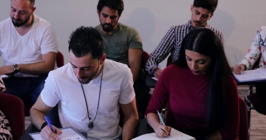 Students writing notes in class|-