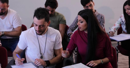 Students writing notes in class|-