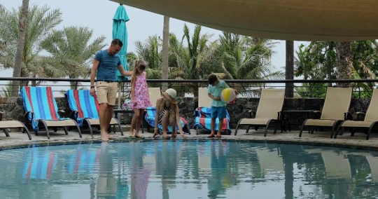 Western Family standing together by the pool|-