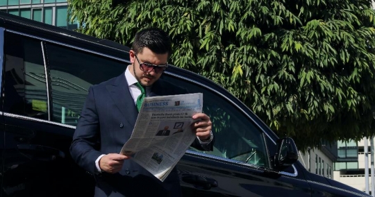 Western Businessman reading the newspaper by the car|-