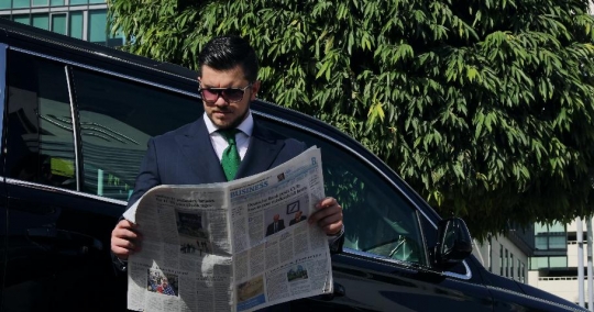 Western Businessman standing next to the car reading the newspaper |-