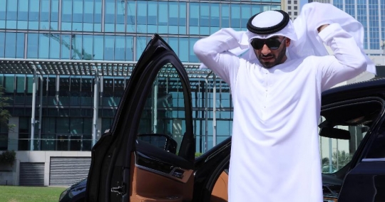 Arab Businessman fixing his kandoura by the car|-