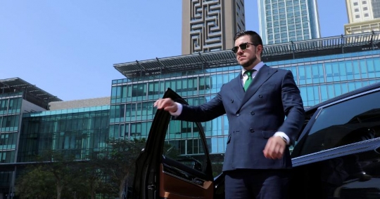 Western Businessman standing next to his car fixing his suit|-