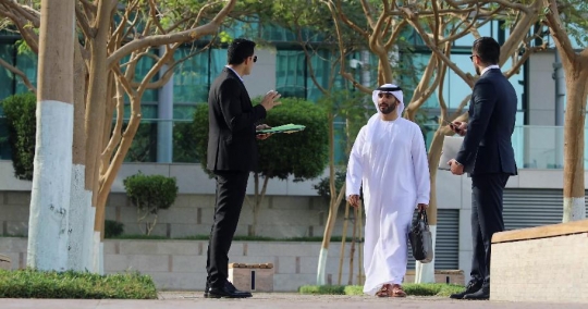 Middle Eastern man walking towards his colleagues |-
