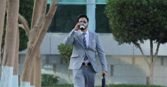 Businessman dressed in a grey suit walking|-