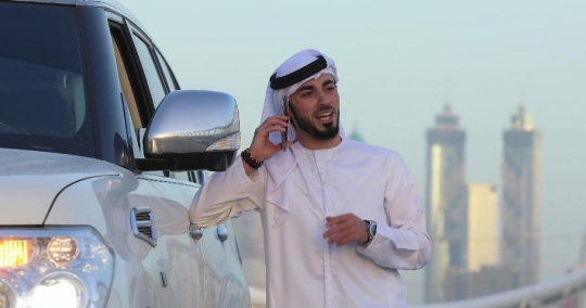 Arab man leaning on the car talking on the phone|-