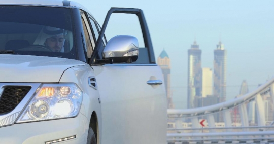 Middle Eastern man steps out of his car looking at his tire|-