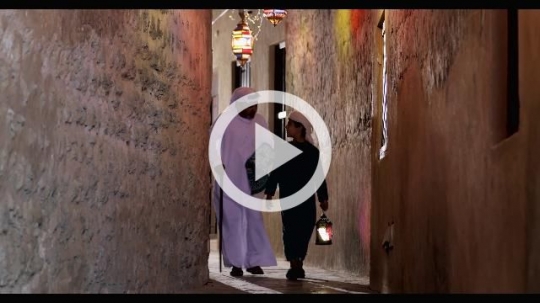 Arab grandfather walking with the young boy carrying a Ramadan Lantern|