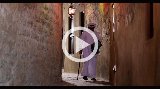 Middle Eastern man walking through the alleyway decorated by Ramadan Lanterns|