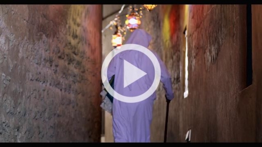 Middle Eastern man walking through the alleyway decorated by Ramadan Lanterns|