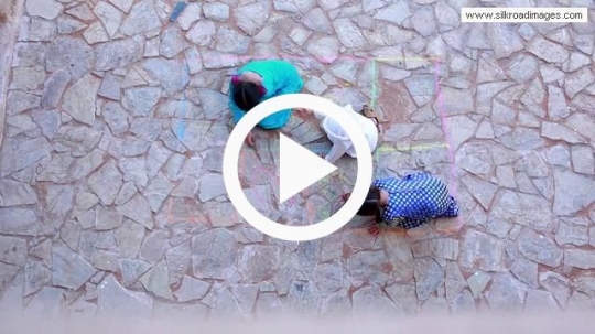 Top view of children sketching on the ground