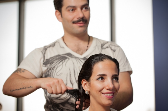 Middle Eastern hairdresser brushing the customers hair|