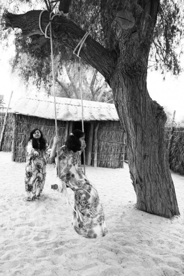 two girls swinging in front of their traditional home