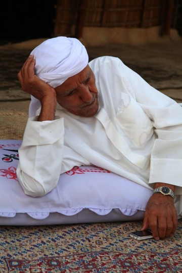 close up of an old man leaning on a pillow