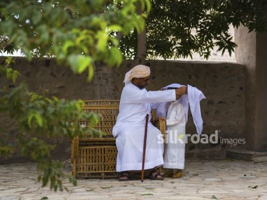 Old mn fixing traditional costume of grandson|-