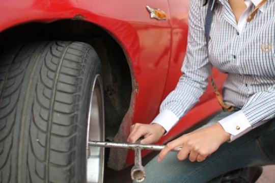 woman  fix  red car wheel 