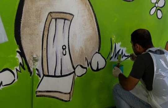 male volunteer painting the wall of a kindergarten