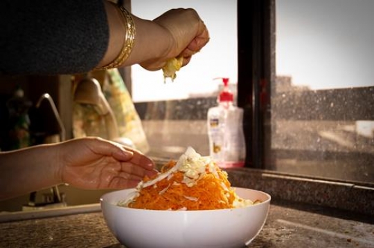 woman adding lemon juice to salad