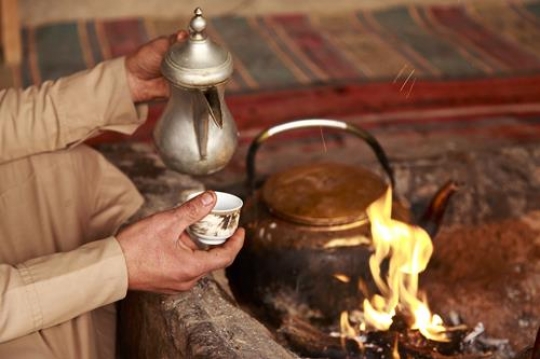 beduin holding a traditional coffee pot with cup