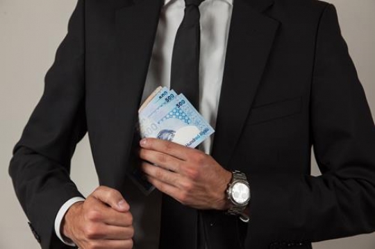 businessman putting money in his pocket