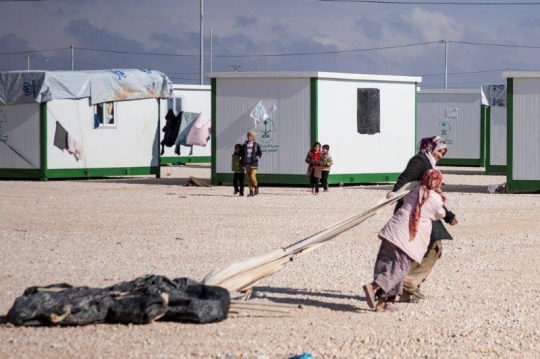kids dragging bags in refugee camp