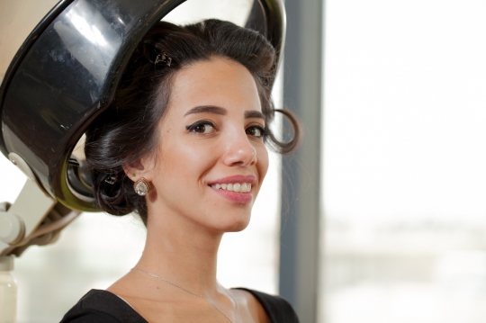 Middle Eastern woman sitting under the hairdryer machine |