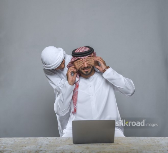 Boy covering father's eyes