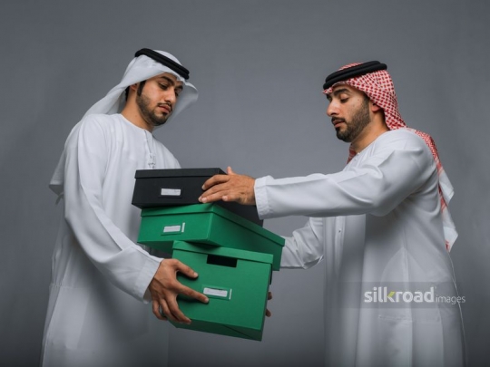 Two arabian men carrying boxes|