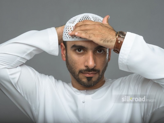 Arabian man fixing his headdress with his hands