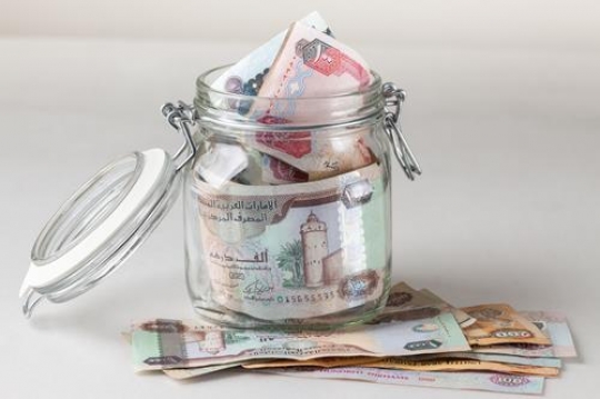 a glass jar filled with uae dirhams