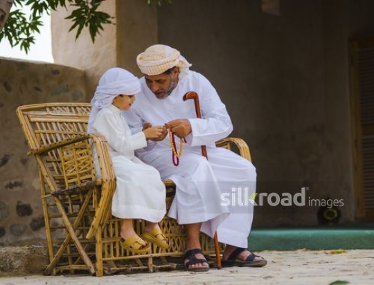 old man showing praying beads to grandson|-
