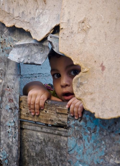 little boy looking through a hole in a wall