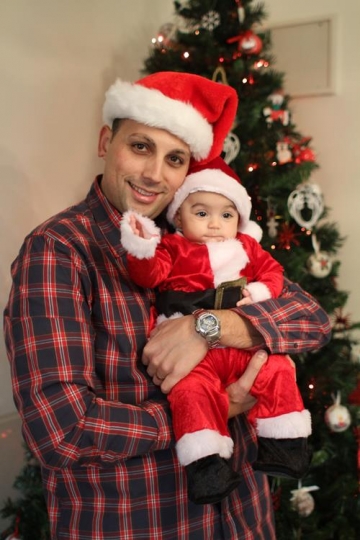 Newborn baby with Santa Hat, held by his father