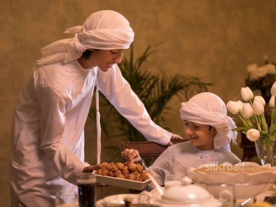 Boy serving brother Arabic sweets|-