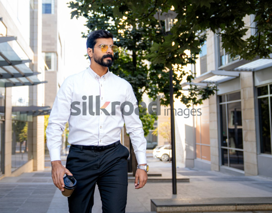 Arab Man Enjoying Coffee While Working Outdoors in Jordan's Al Abdali Boulevar