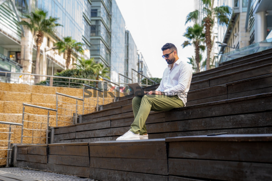 Arab Man Working Outdoors with Laptop in Amman's Abdali Boulevard