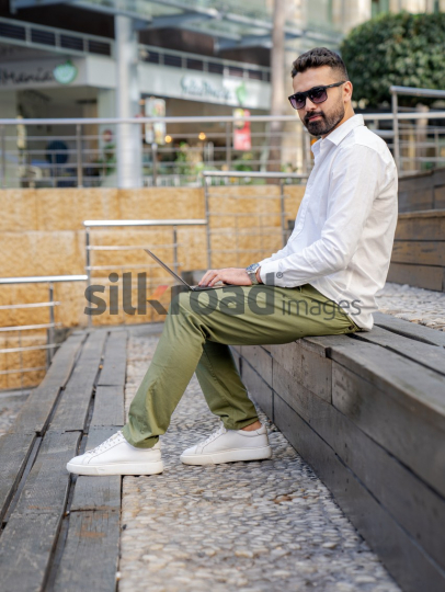 Arab Man Working Outdoors with Laptop in Amman's Abdali Boulevard