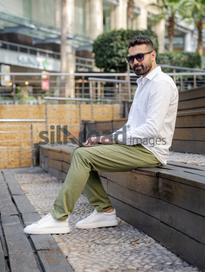 Arab Man Working Outdoors with Laptop in Amman’s Abdali Boulevard